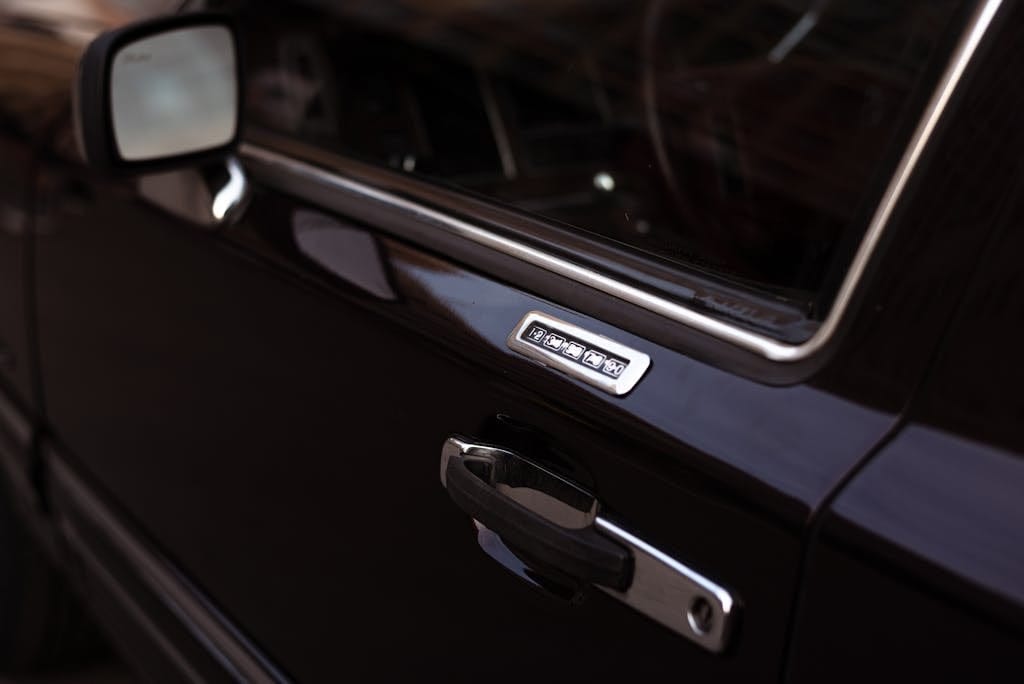 Close-up of a classic black car door with keypad lock, showcasing metallic details.